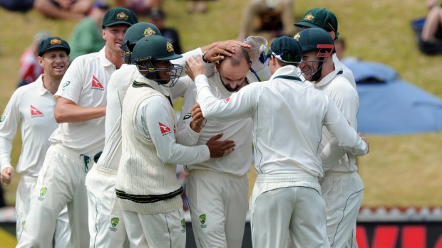 Job done: Australian teammates mob Nathan Lyon after dismissing BJ Watling on day four of the first Test.