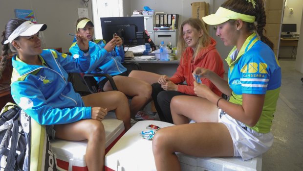Canberra Velocity tennis players (in blue tops) from left Maria Vais, Tyra Calderwood and Imogen Clews, and Sydney University player, Martina Hudaly (orange top), play cards during a rain delay on Saturday. 