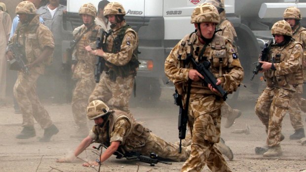 A British trooper falls after being hit by a rock in Basra in 2006.