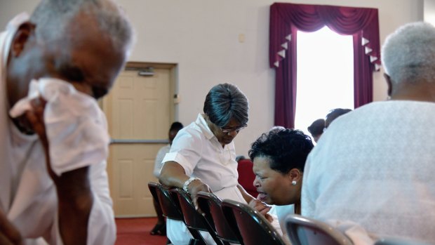 Pastor Jerry Colbert, 64, (left)  the great-grandson of a slave, wipes sweat from his brow as he listens to the prayers of members of a Singing and Praying Band group at the Hall United Methodist Church in Glen Burnie, Maryland.

