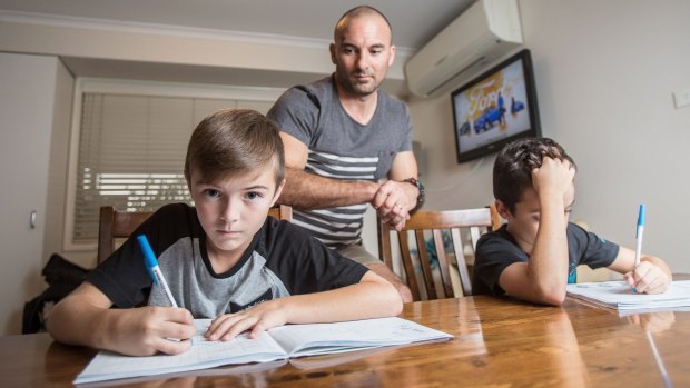 Craig Zammit helps his sons Thomas and Mason with their homework.