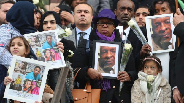 People hold up photos of their loved ones as they leave the Grenfell Tower National Memorial Service at St Paul's Cathedral, in London.