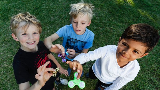 Nixon Conrick, Callum Knight and Rohan Cugati play with their fidget spinners, the latest craze for children and teenagers.