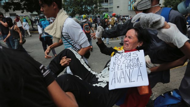 A woman affected by tear gas, fired by security forces, is carried away during a 12-hour national sit-in in Venezuela.