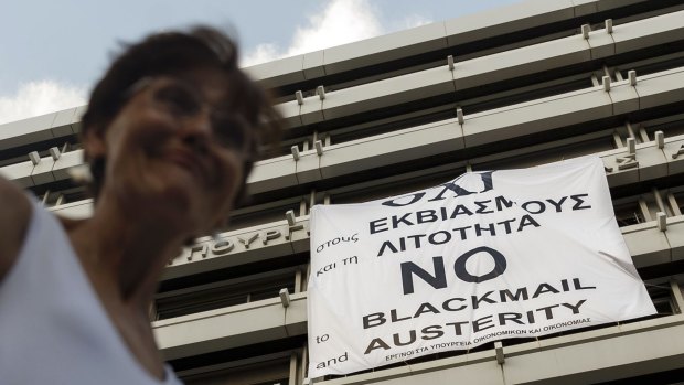 A woman passes a banner supporting the No vote to the upcoming referendum in Athens.