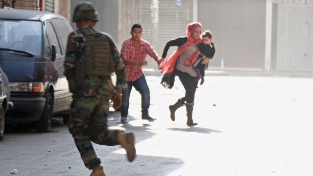 A Lebanese soldier runs past fleeing residents during the clashes in Tripoli, the country's second city, between Lebanese forces and Islamist gunmen.