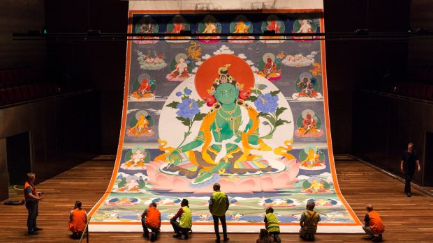 Staff unfurl the giant portrait of Tara at Hamer Hall ahead of White Night.