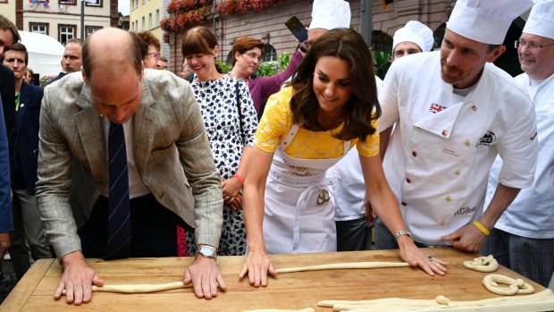 Andreas Goebes of the bakers guild Heidelberg, right, watches as Princess Kate, Prince William, form pastry to pretzels during their visit of the market.