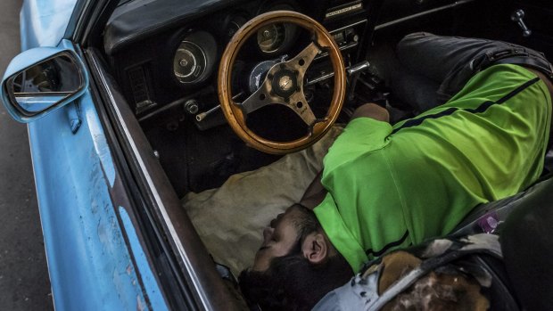 A man sleeps in his car at dawn outside a car-battery shop in Caracas last month. He was one of more than 80 drivers lined up overnight to buy a battery from the limited supply the next day. 