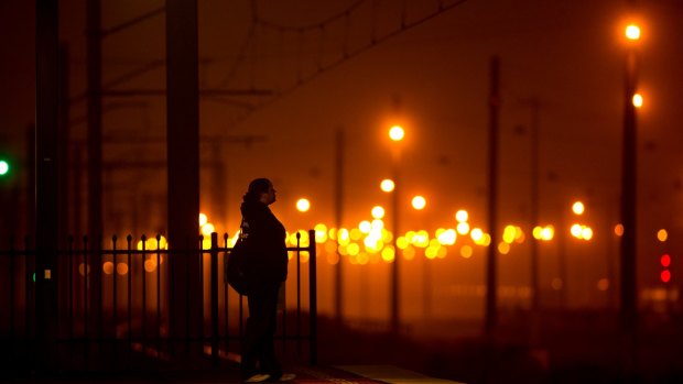 A woman waits in the mist at West Footscray train station. 
