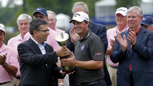 Brian Stuard receives the tournament trophy from Rohit Verma, regional executive for Zurich North America, after winning the rain-delayed Zurich Classic tournament.