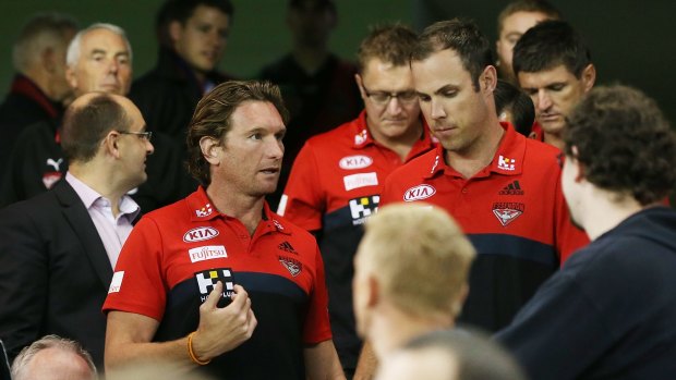 James Hird talks to assistant coach Matthew Egan as he leaves the coaches box during a break in the game.