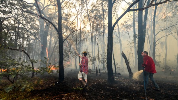 Adam Watkins and partner Prue Mathiesen fight the fire to save their home in Lancefield.