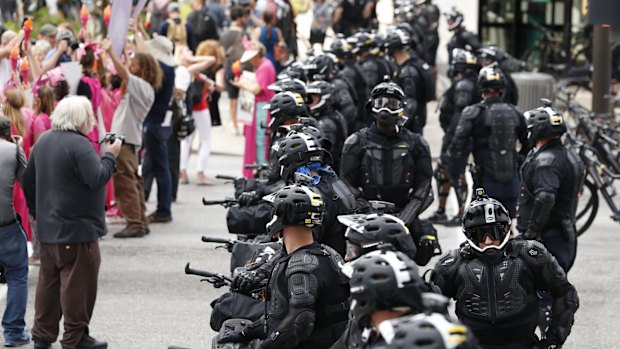 Demonstrators march past police belonging to a specially assembled "bicycle unit", with their handlebars pointing outward, during the "Shut Down Trump" protest rally in Cleveland.