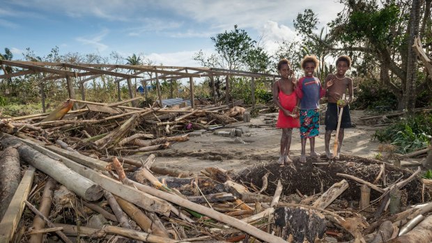 Children stand around the remains of a local community centre destroyed in cyclone Pam in  Port Vila.