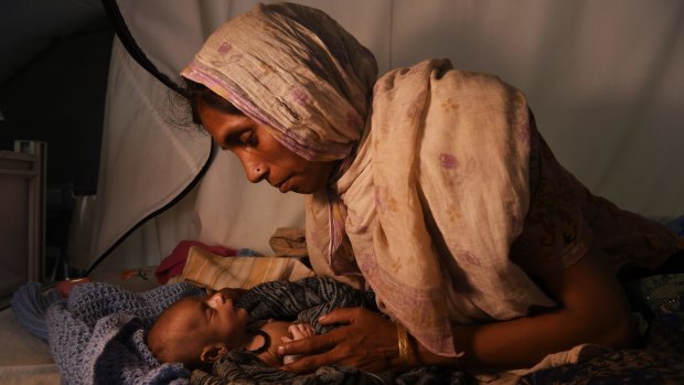 Rohingya woman Laila Begum holds her son Mohammed Ifran's hand as he receives treatment at the Red Cross Field Hospital in Kutupalong refugee camp.
