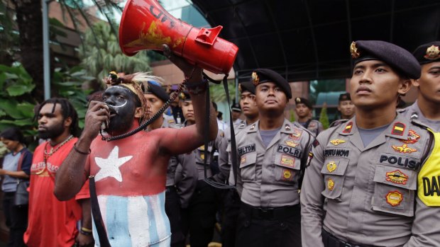 A Papuan activist whose body is painted in the colors of "Morning Star" separatist flag shouts slogans as police officers stand guard during a protest against the U.S. mining giant Freeport-McMoRan Copper & Gold Inc. in Jakarta, Indonesia, Monday, March 20, 2017. A group of activists staged the protest demanding the New Orleans-based mining company close its mine in Papua province saying that it siphons off the region's wealth and gives it little in return. (AP Photo/Achmad Ibrahim)