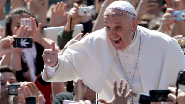 Pope Francis greets the faithful gathered for a Mass in St Peter's Square in the Vatican City with an enthusiastic thumbs up.