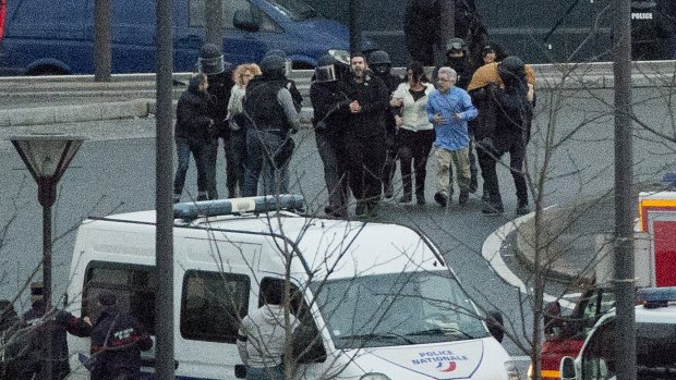Security officers escort released hostages after they stormed a kosher market to end a hostage situation.