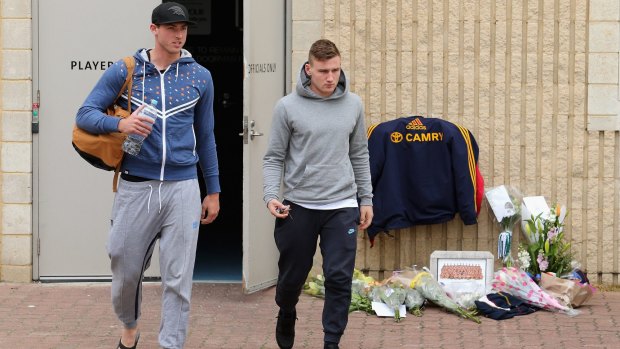 Toughest of days: Daniel Talia and Rory Laird leave the Adelaide club rooms as tributes are left for coach Phil Walsh.