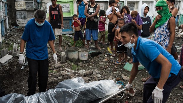Morgue workers carry an unclaimed body and victim of an extrajudicial killing in Manila, Philippines.