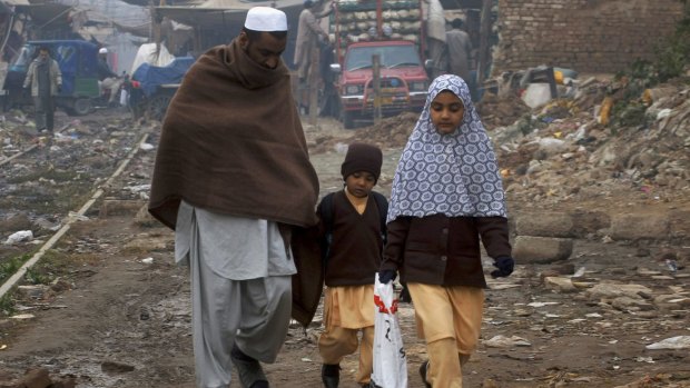 A Pakistani man walks his children home from school in the north-western city of Peshawar on Saturday. 