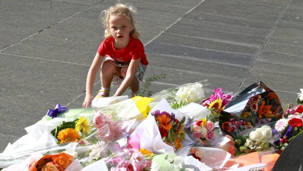 A child lays flowers for the hostages killed in the siege in Martin Place that ended early Tuesday morning.