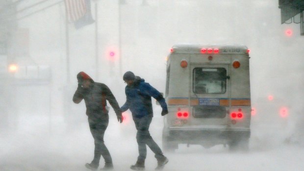 Pedestrians cross the street in downtown Boston as a massive winter storm swept from the Carolinas to Maine.