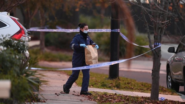 A forensics officer carries evidence from the Deer Park home on Tuesday morning.