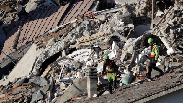 Rescuers make their way through destroyed houses at Pescara Del Tronto.
