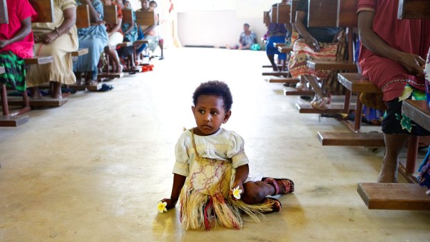 A girl sits it the aisle of the Catholic church during Mass on Manus Island, Papua New Guinea, in 2013. The church is one of the major providers of health care in PNG's remote communities.