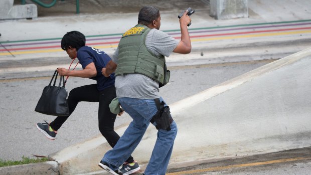 A law enforcement officer evacuates a civilian from an area at Fort Lauderdale.