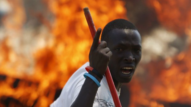 A protester stands in front of a burned barricade during a protest against Burundian President Pierre Nkurunziza's decision to run for a third term in Bujumbura, Burundi on Wednesday.