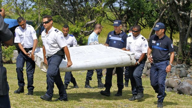 French police officers carry the flaperon which washed up on Reunion Island in July last year. It was later confirmed to be from the missing plane.
