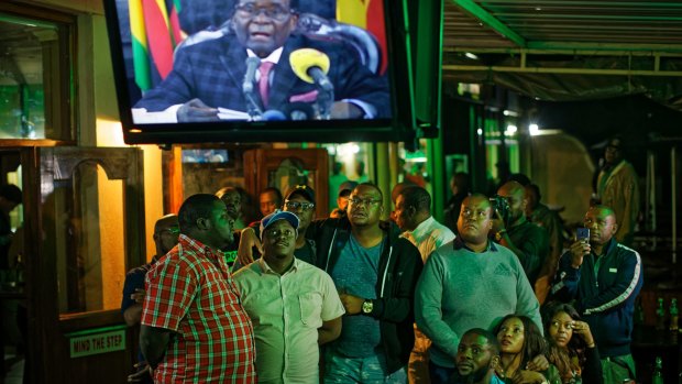 Zimbabweans watch a televised address to the nation by President Robert Mugabe at a bar in downtown Harare, Zimbabwe.