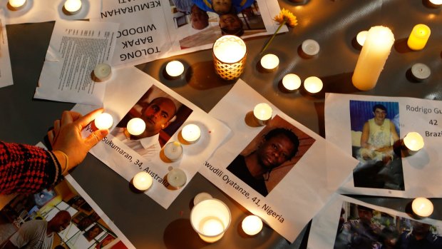 A woman places a candle on top of pictures of the prisoners at a vigil in Sydney on Tuesday night ahead of the executions in Indonesia.