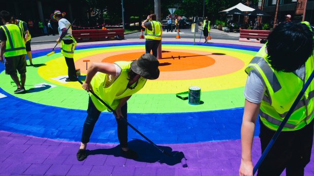 Members of the community paint the final touches on the rainbow roundabout on the corner of Elouera St and Lonsdale St in Braddon.