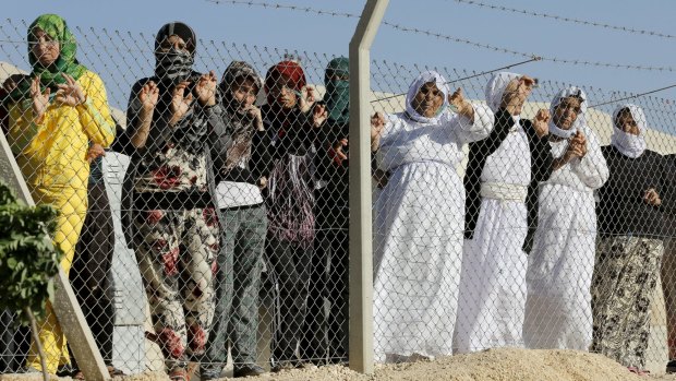 Yazidi refugee women stand behind fences as they wait for the arrival of Angelina Jolie.