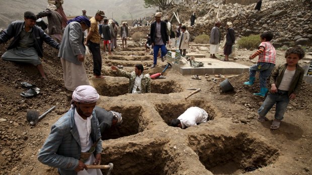 People dig graves for the victims of an air strike in Okash village near Sanaa on Saturday.