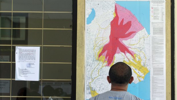 A man observes a map of the Mount Agung volcano at the Mount Agung monitoring station.
