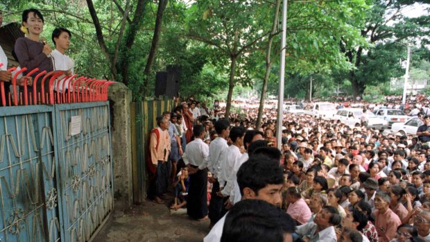 Aung San Suu Kyi  addresses her supporters from the gates of her house in July 1996.