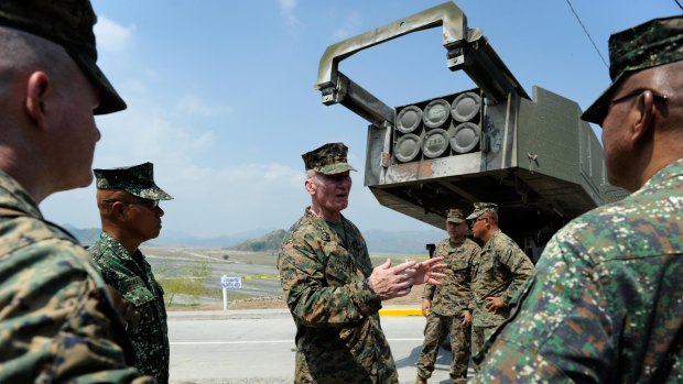 US Lieutenant General John Toolan (cemtre) stands behind a High Mobility Artillery Rocket System.