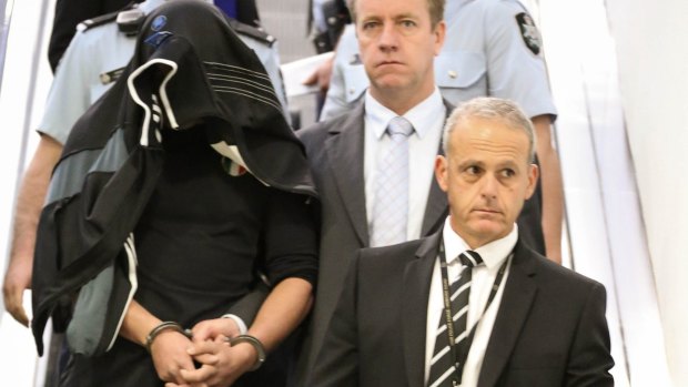 Detectives escort Diego Carbone out of Sydney International Airport after his arrest in 2014.