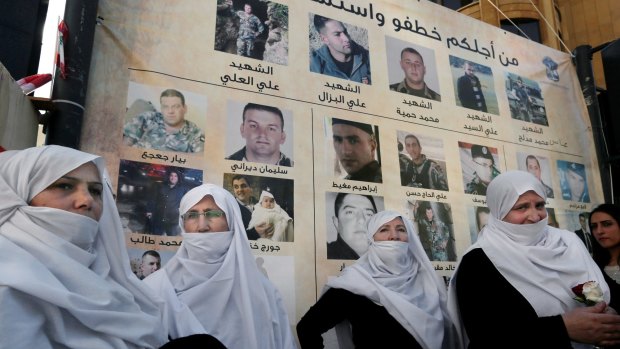 Lebanese Druze women stand next to posters with pictures of the soldiers and policemen kidnapped and in some cases killed by the Nusra Front and Islamic State.