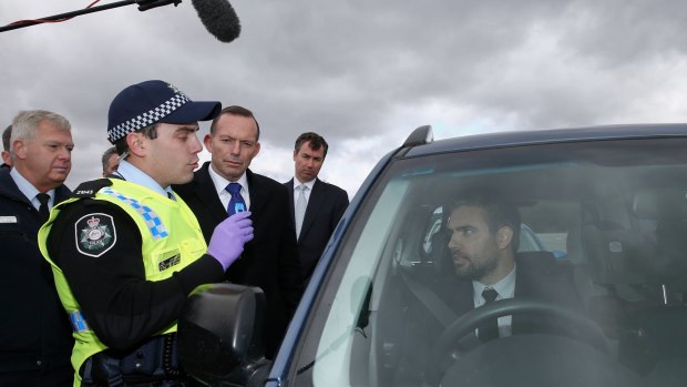 Prime Minister Tony Abbott observes a staged drug test during his visit to an AFP training facility.