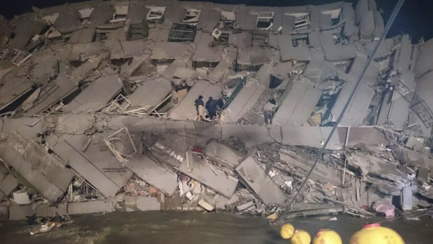 Rescuers entering a collapsed office building in Tainan.