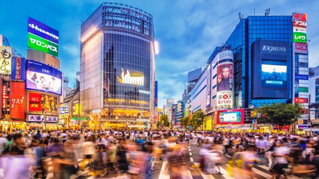 The famous Shibuya Crossing in Tokyo during rush hour at dusk. 