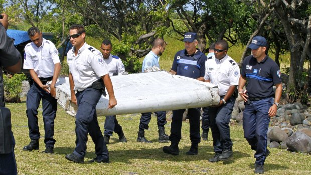 French police officers carry the flaperon that washed up on Reunion Island in July last year.