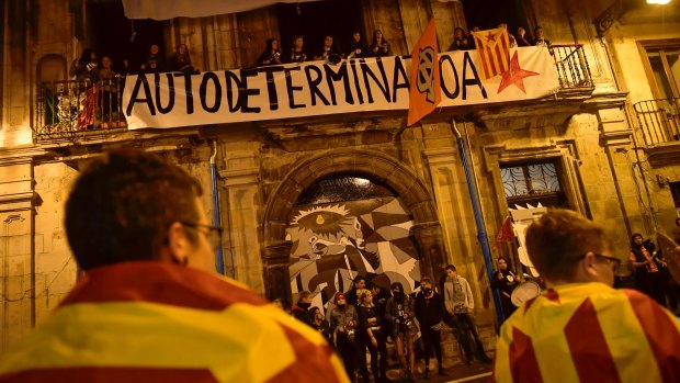 Pro independence supporters wrapped by ''esteleda'' or Catalan pro independence flags in front a balcony with a banner reading, ''self determination'' in support of the Catalonia's secession referendum.