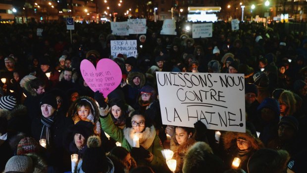 People attend a vigil in Montreal for victims of Sunday's shooting at a Quebec City mosque. Sign reads "let's unite against hatred".